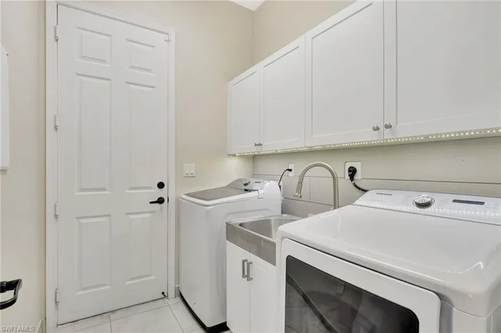 Laundry area featuring Samsung washer and dryer, cabinets, custom farmhouse sink, under cabinet lighting