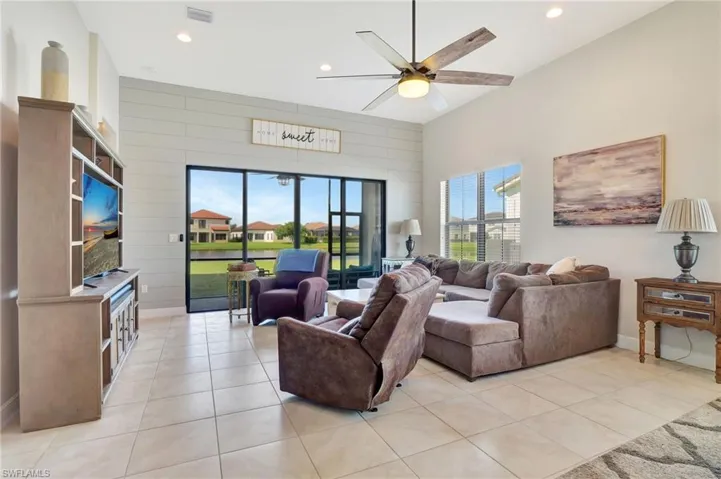 Great room featuring shiplap wall, ceiling fan, and light tile patterned floors