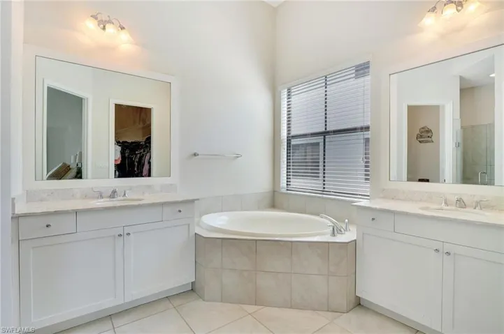 Master Bathroom featuring dual vanities, plus soaking tub and tile patterned flooring