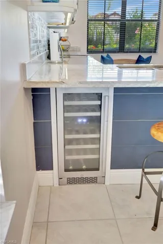 Bar featuring light stone counters, wine cooler, with shiplap accent
