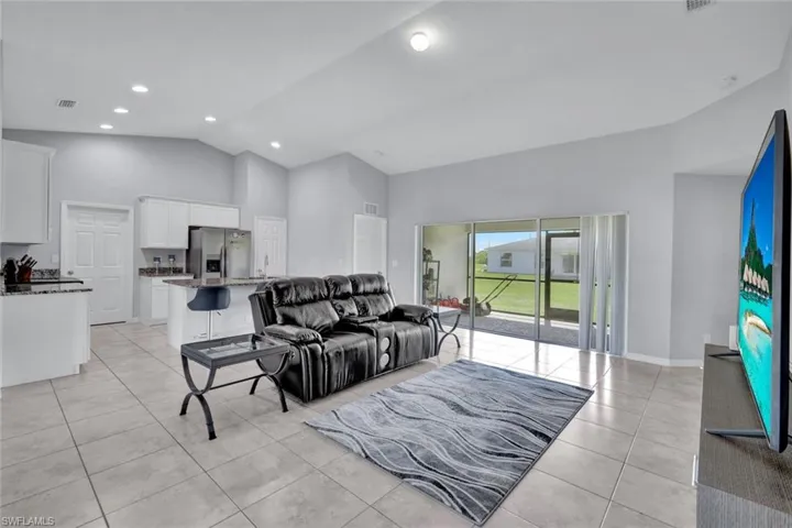 Living room with high vaulted ceiling, light tile patterned floors, and recessed lighting