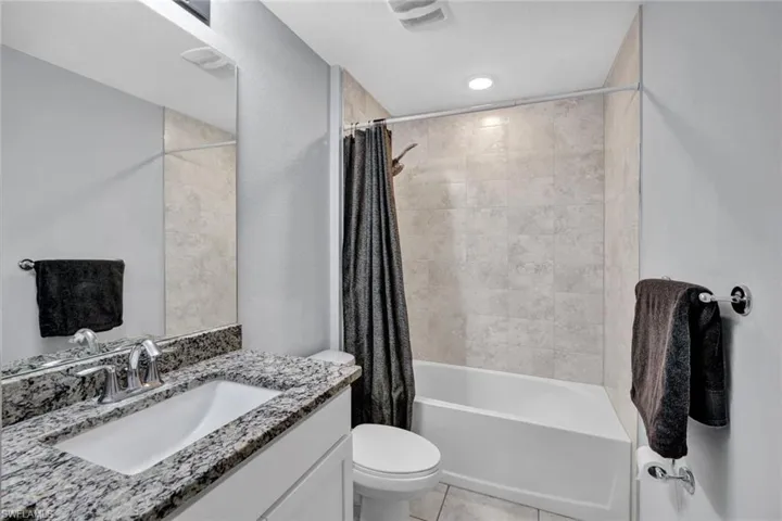 Bathroom with shower / bathtub combination with curtain, vanity, and light tile patterned floors