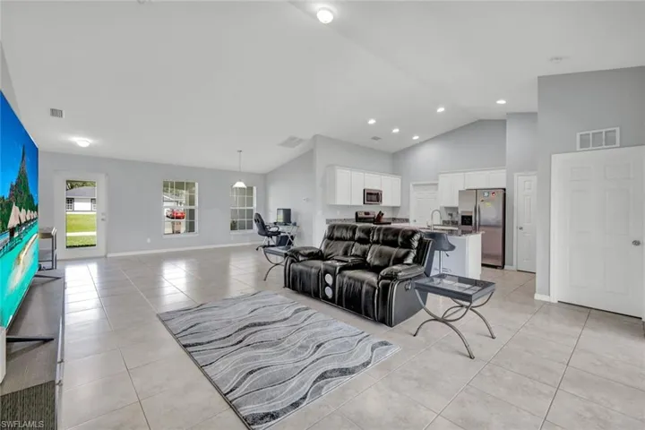 Living room featuring light tile patterned floors, high vaulted ceiling, and recessed lighting