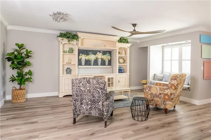 Sitting room featuring ornamental molding, a ceiling fan, baseboards, and light wood-type flooring