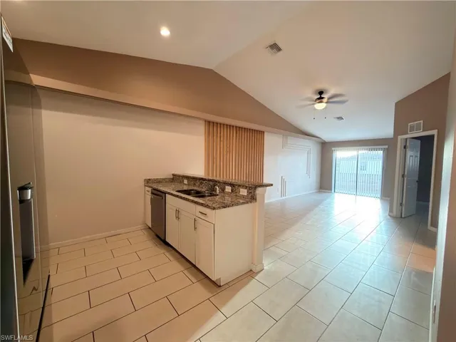 Kitchen with white cabinetry, dark stone countertops, stainless steel appliances, open floor plan, and ceiling fan