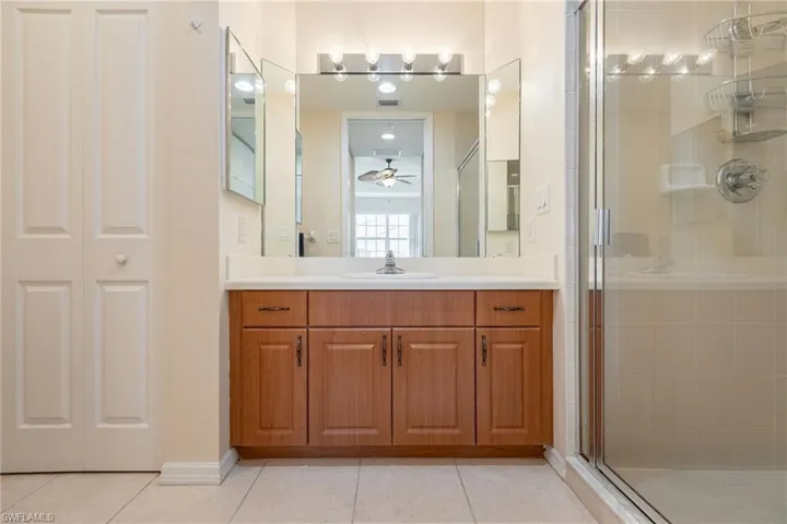 Full bathroom featuring a closet, vanity, a stall shower, light tile patterned floors, and a ceiling fan