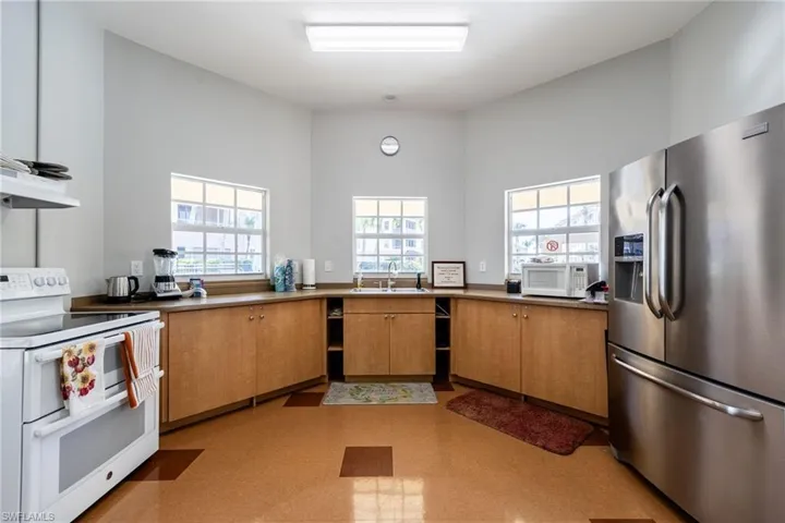 Kitchen featuring white appliances, plenty of natural light, exhaust hood, and wood finish cabinets