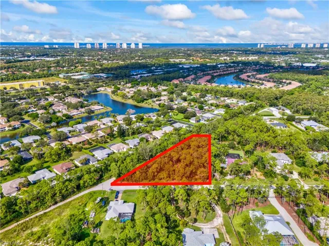 Aerial view of property and surrounding area featuring a large body of water, property boundaries highlighted, and nearby suburban area