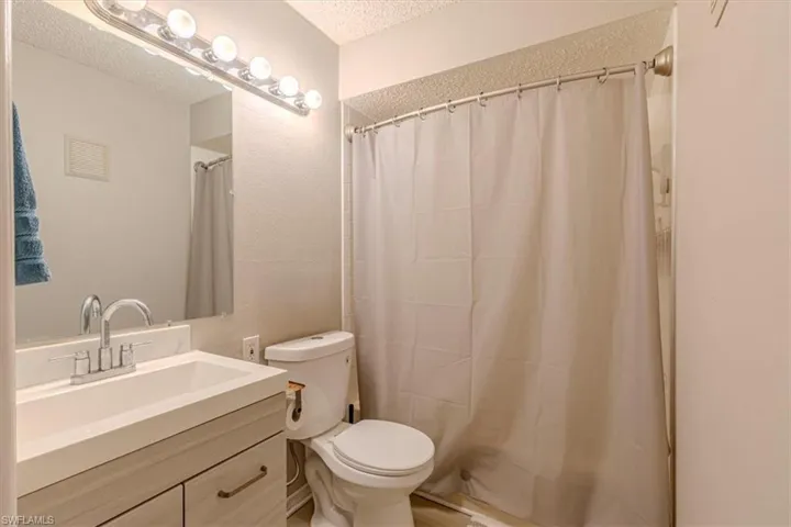 Full bathroom with vanity, a shower with shower curtain, and a textured ceiling