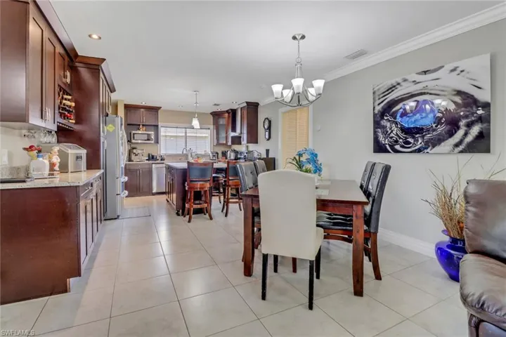 Dining area featuring light tile patterned floors, ornamental molding, visible vents, recessed lighting, and a notable chandelier