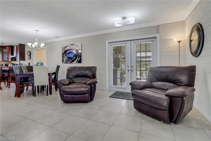 Living area with a chandelier, french doors, crown molding, and light tile patterned flooring
