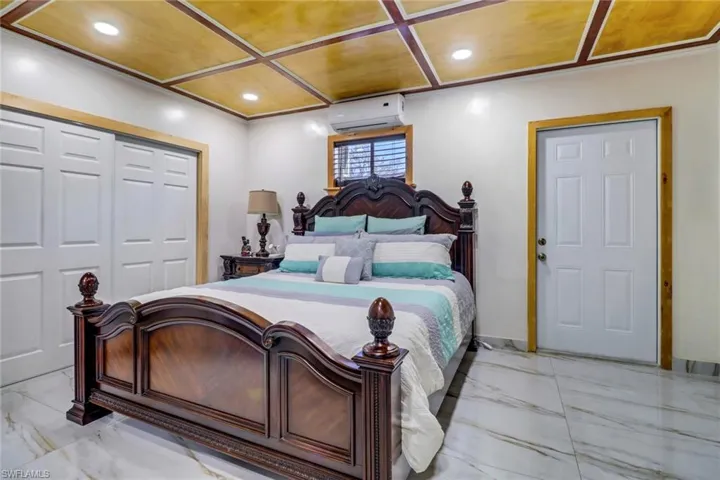 Bedroom with a closet, recessed lighting, marble finish floor, and a wall unit AC