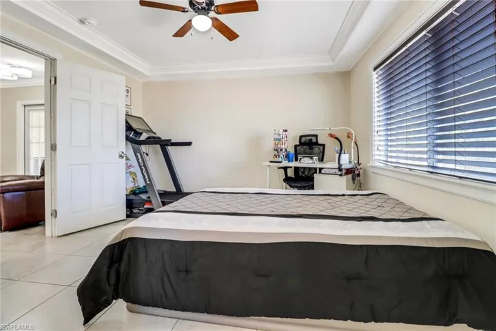 Bedroom with crown molding, light tile patterned floors, multiple windows, and a ceiling fan