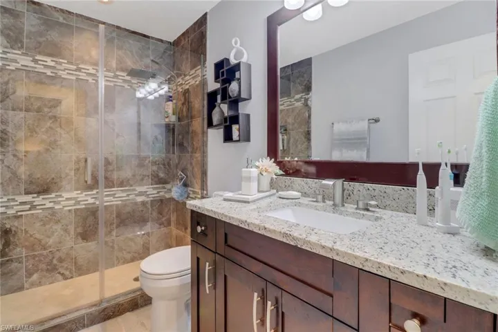 Full bath featuring a shower stall, vanity, and toilet