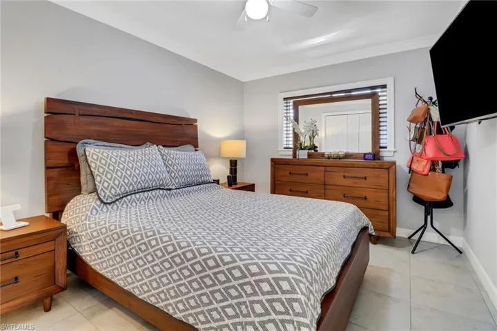 Bedroom with light tile patterned floors, baseboards, crown molding, and ceiling fan