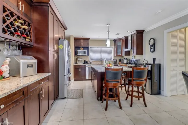 Kitchen featuring ornamental molding, light tile patterned floors, a breakfast bar, and stainless steel appliances