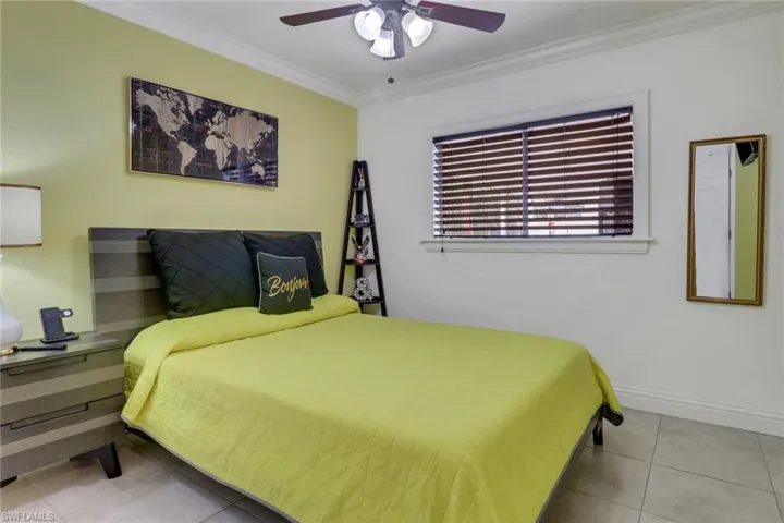 Bedroom with tile patterned floors, baseboards, crown molding, and ceiling fan