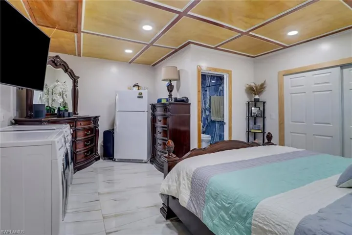 Bedroom with recessed lighting, freestanding refrigerator, connected bathroom, coffered ceiling, and marble finish floor