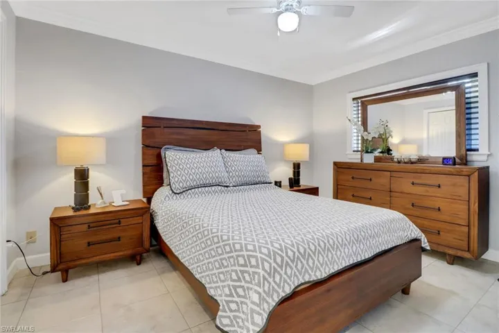 Bedroom featuring a ceiling fan, tile patterned floors, baseboards, and ornamental molding