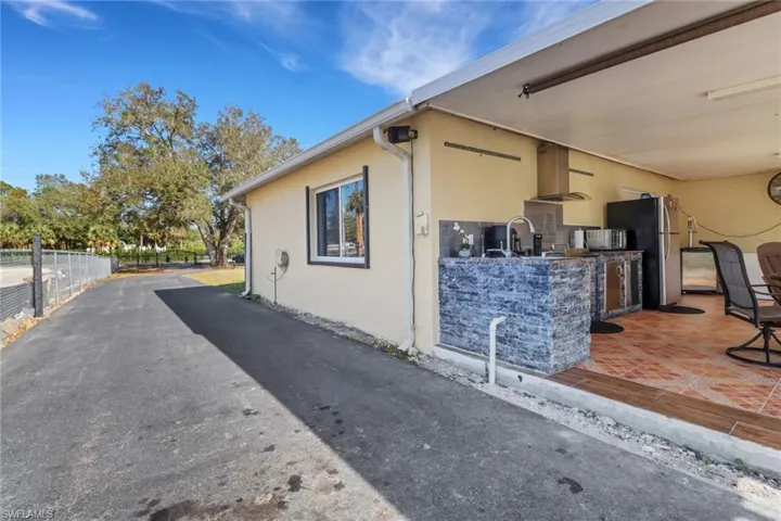 View of property exterior with a patio area, a sink, area for grilling, fence, and stucco siding