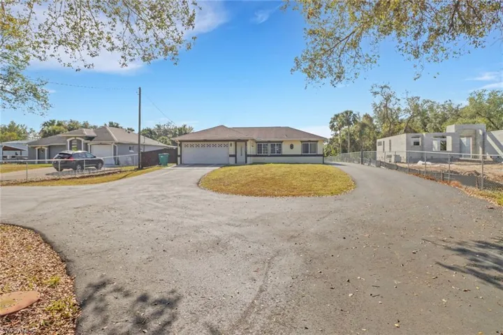Ranch-style house with a garage, a residential view, driveway, and fence