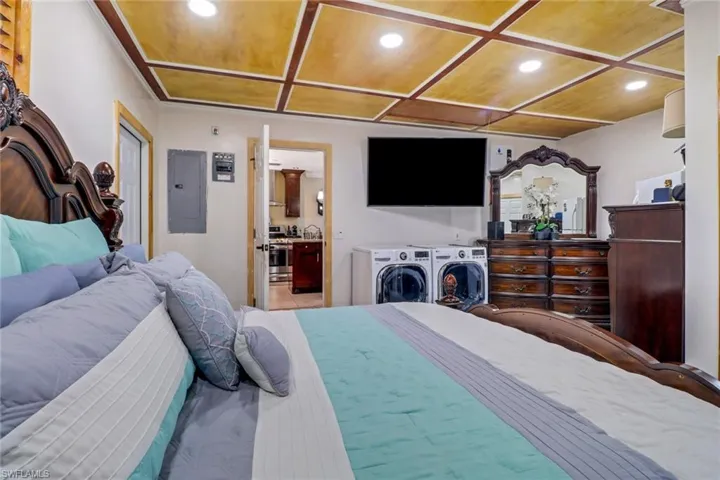 Bedroom with electric panel, recessed lighting, connected bathroom, independent washer and dryer, and coffered ceiling