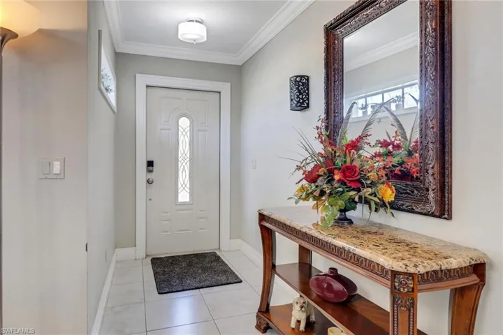 Entryway with baseboards, ornamental molding, and light tile patterned flooring
