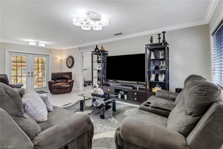 Living area with french doors, an inviting chandelier, ornamental molding, and a healthy amount of sunlight