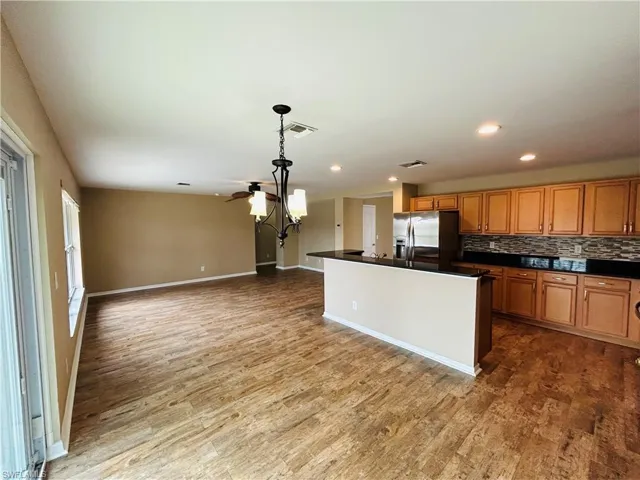 Kitchen featuring wood finish cabinets, stainless steel fridge, decorative backsplash, a center island, and open floor plan