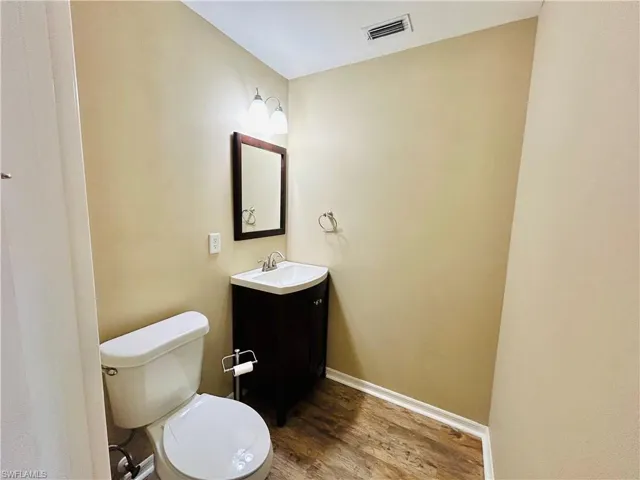 Half bathroom featuring vanity and dark wood-type flooring