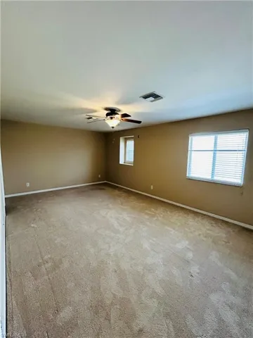 Empty room with light colored carpet and ceiling fan