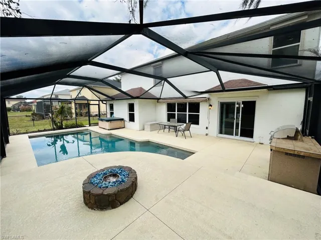 Outdoor pool featuring a patio area, glass enclosure, a sunroom, and a hot tub
