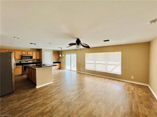 Kitchen with stainless steel appliances, open floor plan, a kitchen island, and dark wood finished floors