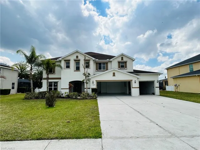 View of front of property featuring stucco siding, concrete driveway, a front yard, and an attached garage