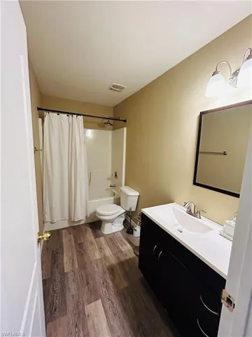 Full bathroom featuring vanity, shower / bath combo with shower curtain, and dark wood finished floors