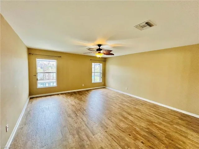 Master bedroom with light wood finished floors and a ceiling fan
