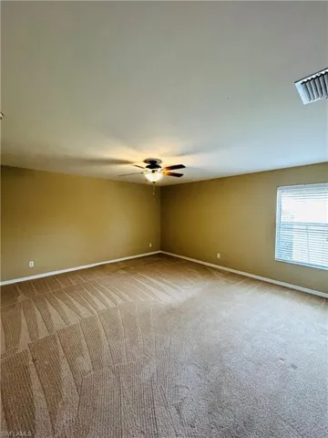 Unfurnished room featuring light colored carpet and a ceiling fan