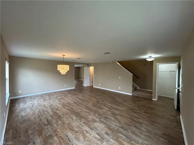 Unfurnished living room with dark wood finished floors and a chandelier