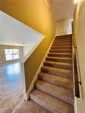 Stairway featuring baseboards and hanging lights