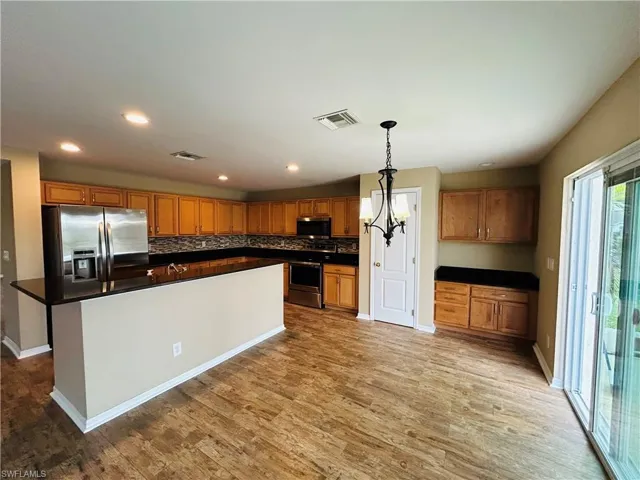 Kitchen with wood finish cabinetry, stainless steel appliances, and dark countertops