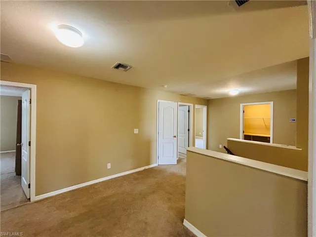 Hallway featuring an upstairs landing and light carpet