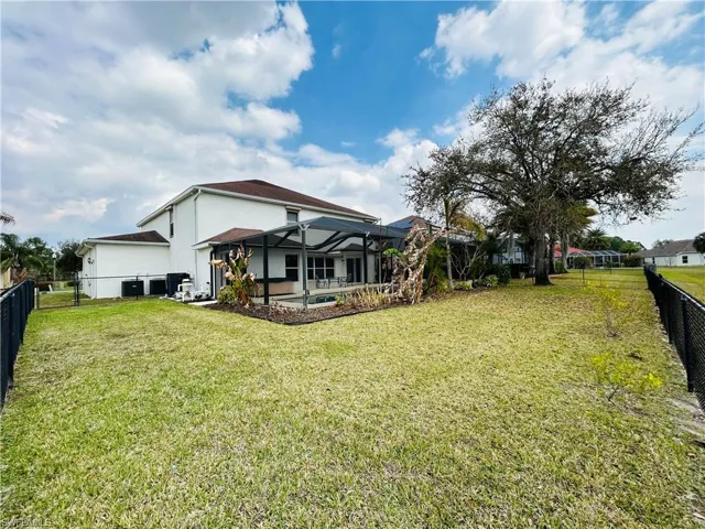 Back of house with a fenced backyard, a lanai, stucco siding, and a patio
