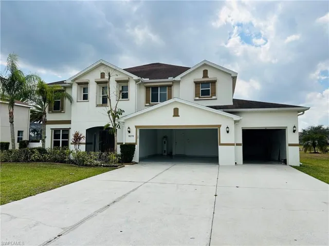 View of front facade featuring stucco siding, driveway, a garage, and a front yard