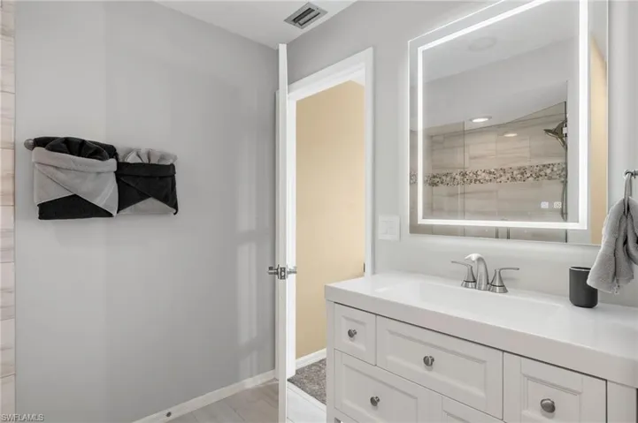 Bathroom featuring tiled shower and vanity