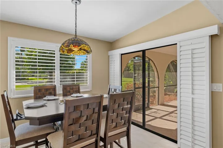 Tiled dining room featuring vaulted ceiling