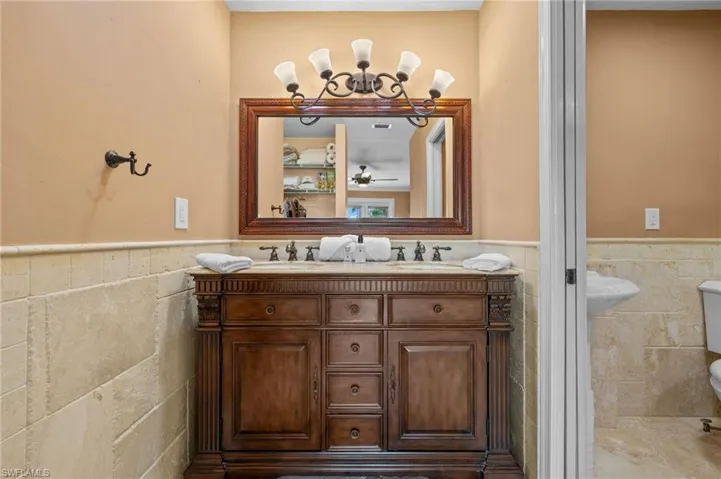 Bathroom featuring double vanity, tile walls, and toilet