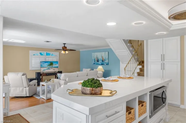 Kitchen featuring stainless steel microwave, a center island, white cabinets, and ceiling fan