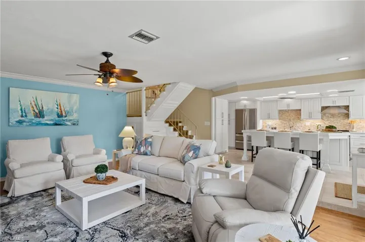 Living room with light hardwood / wood-style floors, ornamental molding, and ceiling fan