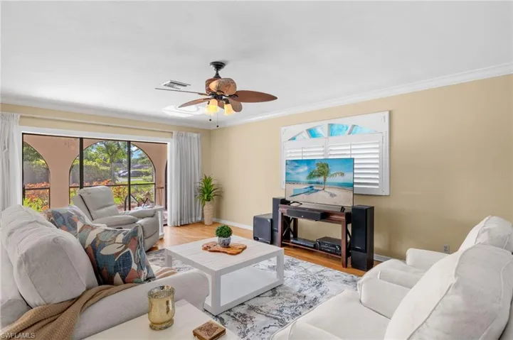 Living room featuring hardwood / wood-style flooring, crown molding, and ceiling fan