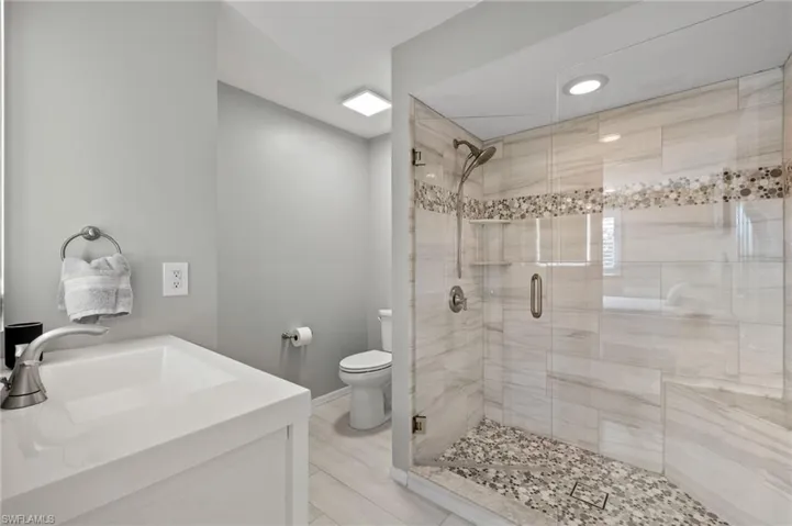 Bathroom with vanity, toilet, and an enclosed shower